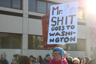 A woman carries a sign that says 